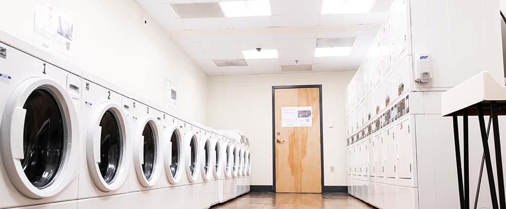 Full service laundry room with machines on each side and a door in the middle