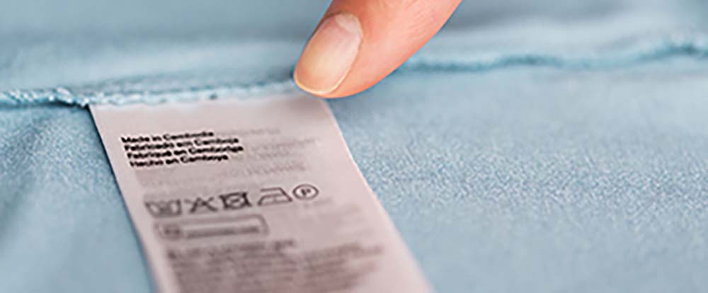 A finger pointing to a tag on a piece of clothing