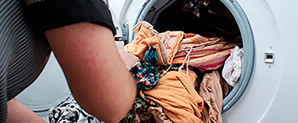 A person putting clothes into a laundry machine