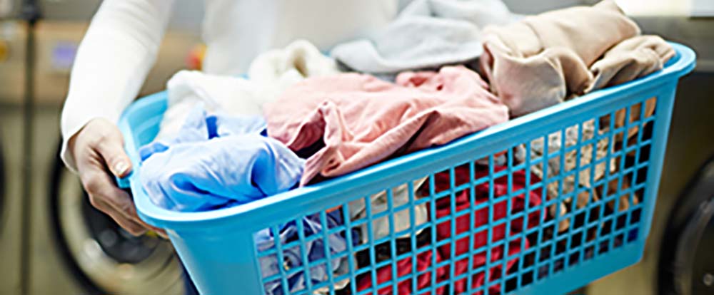 A laundry basket filled with laundry items is being carried