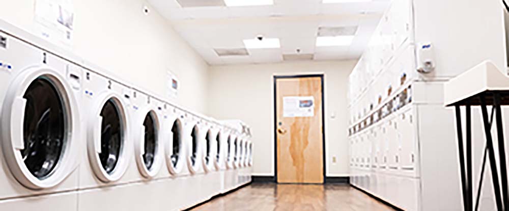 Full service laundry room with machines on each side and a door in the middle