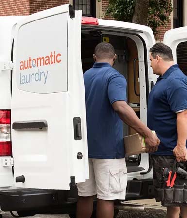 Two men stand outside the back of an Automatic Laundry van